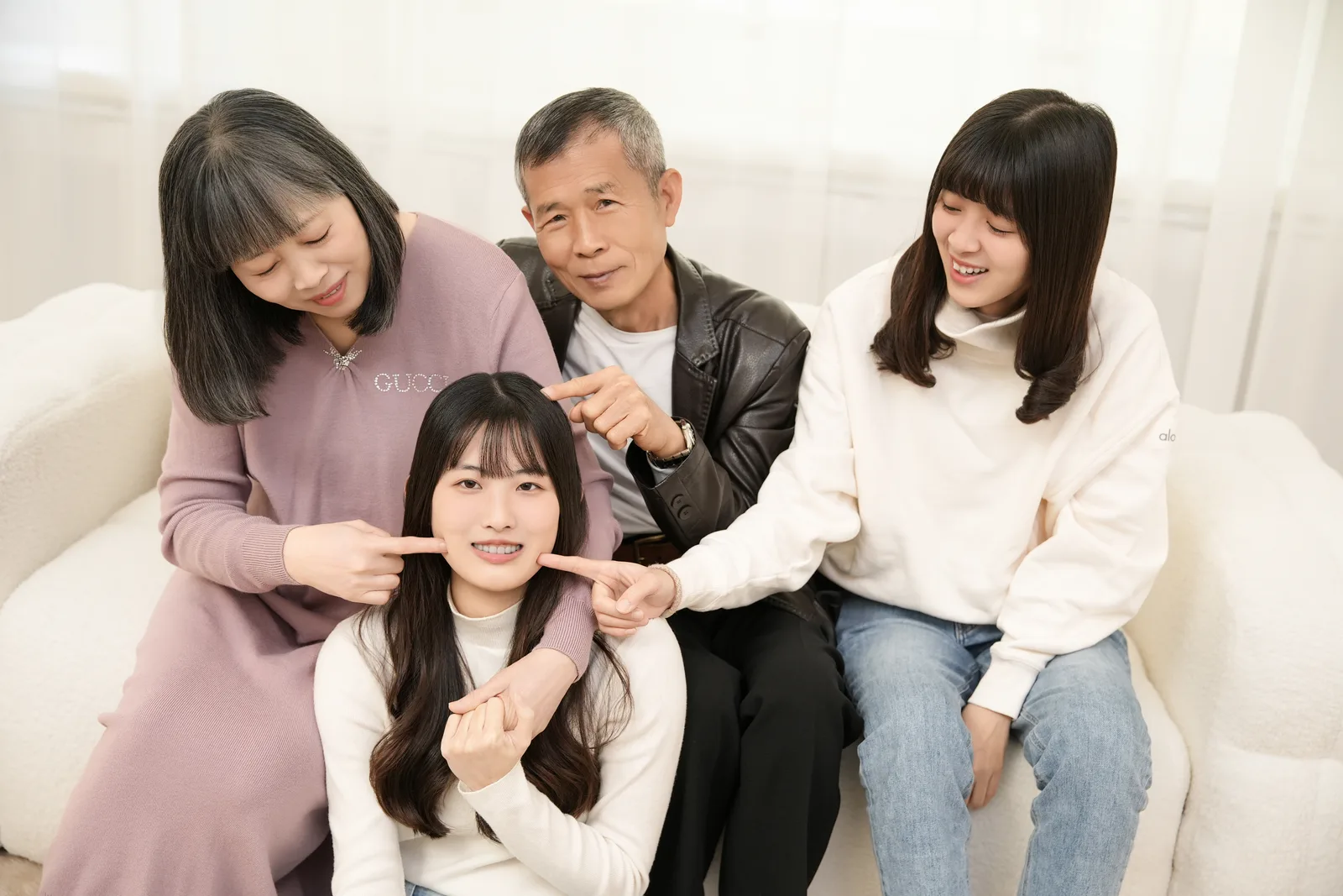 淺色沙發上的四人家庭小組合照,家人靠近彼此微笑互動