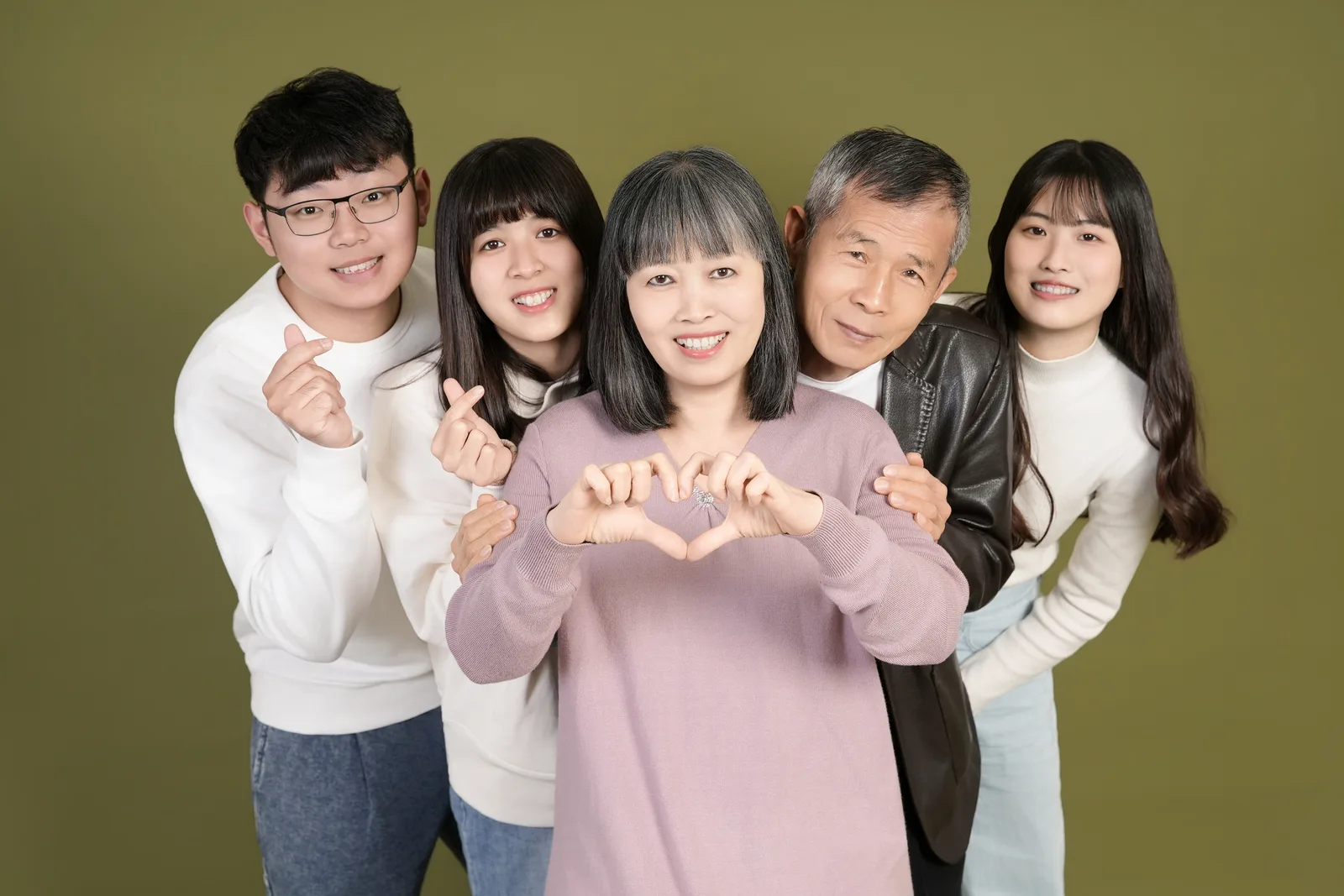 綠色背景的五人家庭合照,家人在畫面中央靠近彼此