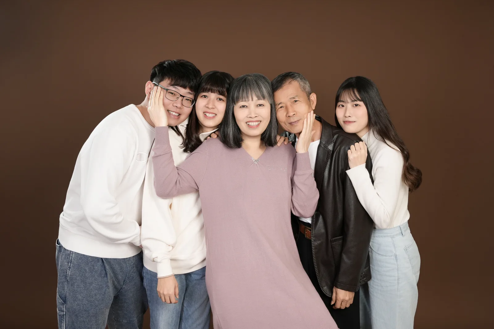 暖棕色背景的五人全家福,家人並肩靠近,微笑看向鏡頭