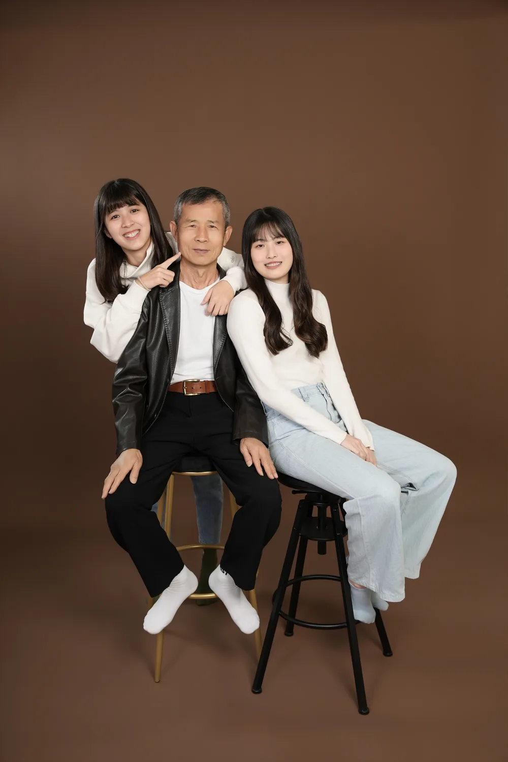 暖棕色背景直幅三人家庭合照,家人圍著坐在中間的家人合影