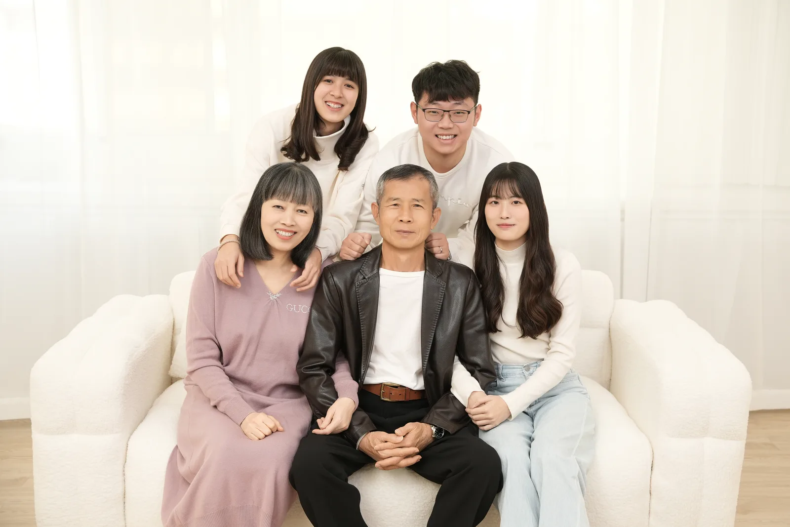 白色沙發棚景的五人全家福,家人以坐姿與站姿錯落合照