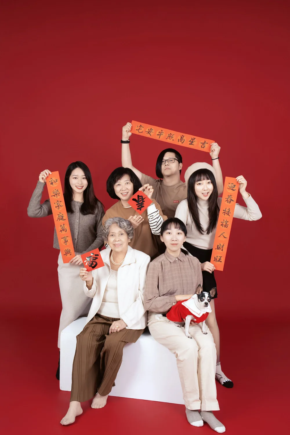 紅色背景全家福,長輩坐在前排,家人站在後排並手持紅色小道具