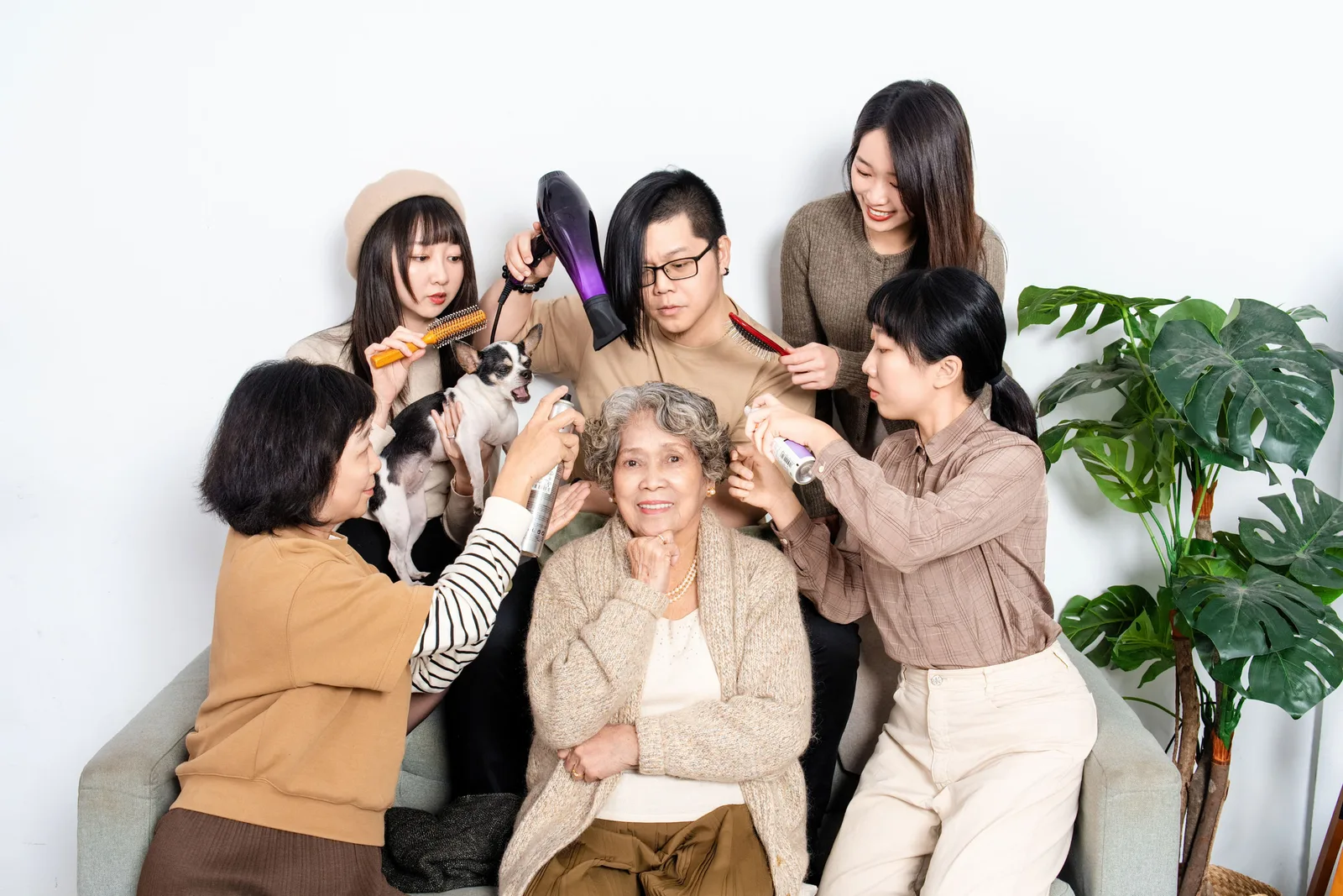 白色棚景中的家庭互動,家人圍著坐在中間的長輩與小狗,互相望向彼此
